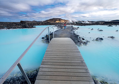 A pier leading down over a blue lagoon with mountains